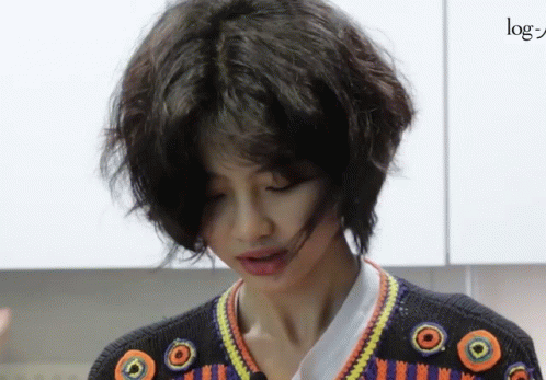 A Woman With Short Hair Is Wearing A Sweater With Circles On The Sleeves GIF