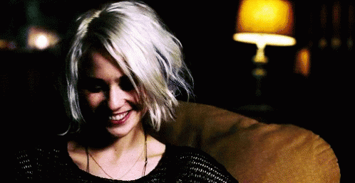 A Woman With Short White Hair Is Sitting On A Couch And Smiling . GIF