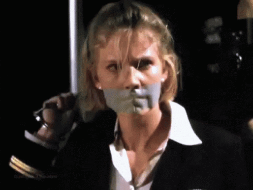 A Woman With Tape On Her Mouth Is Holding A Knife . GIF