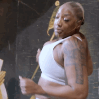 a woman with tattoos on her arms is wearing a white tank top and dancing .