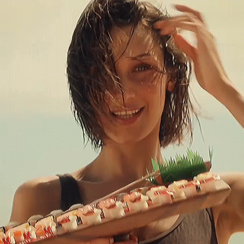A Woman With Wet Hair Is Holding A Tray Of Sushi GIF