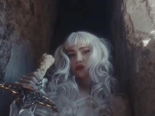 A Woman With White Hair Is Holding A Sword In Her Hand GIF