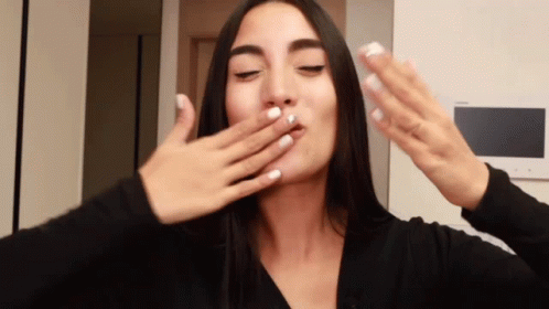A Woman With White Nails Is Covering Her Mouth With Her Hand GIF