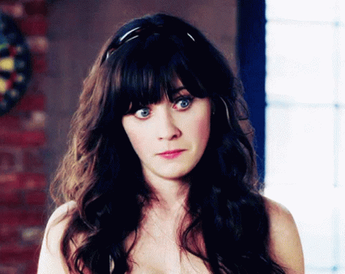 A Woman Without A Shirt Is Looking At The Camera With A Dart Board In The Background GIF