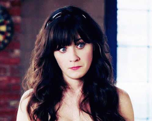 A Woman Without A Shirt Is Looking At The Camera With A Dart Board In The Background GIF
