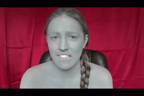 a woman without a shirt is sitting in front of a red cloth