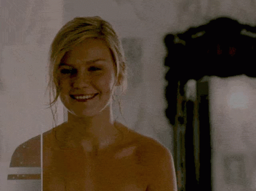 A Woman Without A Shirt Is Smiling And Looking At The Camera GIF