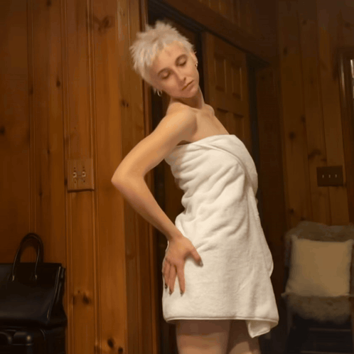 A Woman Wrapped In A White Towel Stands In A Room GIF