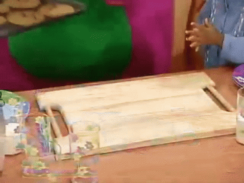 A Wooden Cutting Board Is Sitting On A Table GIF
