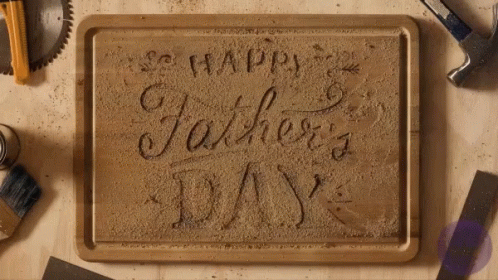 A Wooden Cutting Board With The Words Happy Father 'S Day Carved Into It GIF
