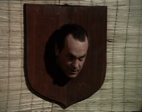 A Wooden Plaque With A Man 'S Head In It GIF