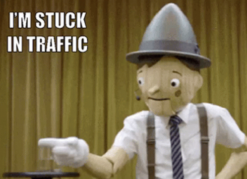 A Wooden Puppet Says I 'M Stuck In Traffic While Pointing A Finger GIF