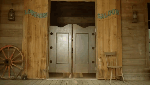 A Wooden Saloon With A Wagon Wheel And A Chair GIF