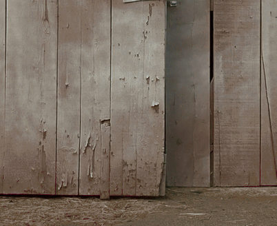 A Wooden Shed With The Door Open And A Few Pieces Of Hay On The Ground GIF