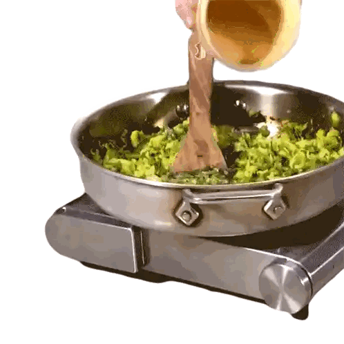 a wooden spoon is being poured into a pan of greens