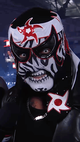 A Wrestler In A Black And White Mask With A Red Star On It GIF