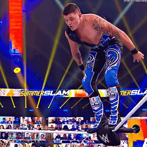 A Wrestler In A Blue And Black Outfit Is Standing On A Rope In Front Of A Banner That Says Summerslam GIF