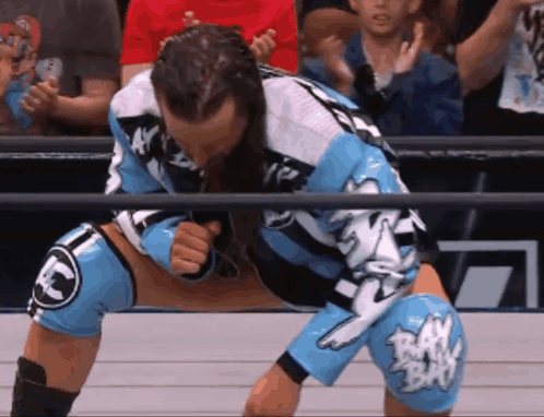 A Wrestler In A Blue And White Uniform With Raw Written On His Knees GIF