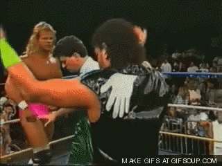 A Wrestler In A Green And Black Outfit Is Standing In A Ring GIF