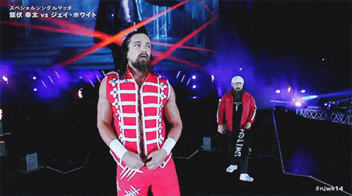 a wrestler in a red and white outfit is walking down a ramp