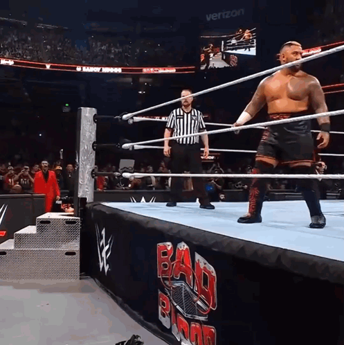 A Wrestler In A Ring With A Referee And A Banner That Says Bad Blood GIF