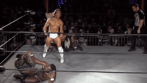 A Wrestler In A Ring With A Referee In The Background GIF