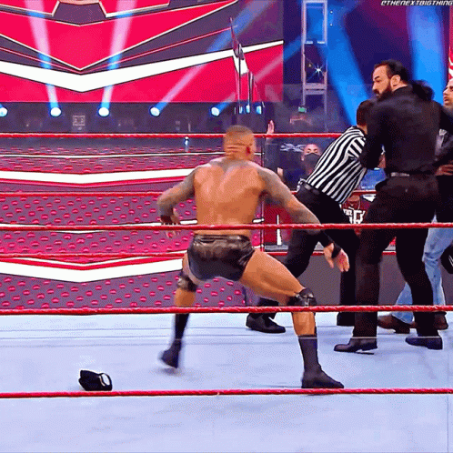 A Wrestler In A Wrestling Ring With A Referee Behind Him And The Word Ethenext Thing On The Bottom Right GIF