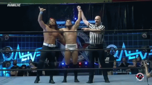 A Wrestler Is Being Congratulated By Another Wrestler In The Ring GIF