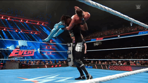 a wrestler is being lifted in the air by another wrestler during a match