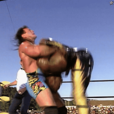 A Wrestler Is Being Lifted Up By Another Wrestler In A Ring GIF