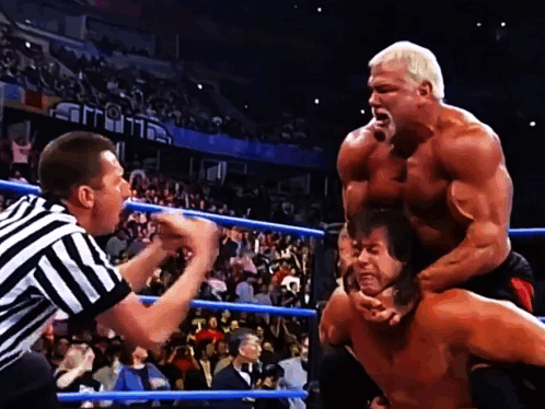 A Wrestler Is Being Lifted Up By Another Wrestler While A Referee Looks On GIF