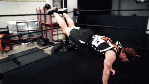 A Wrestler Is Doing A Handstand In A Ring . GIF