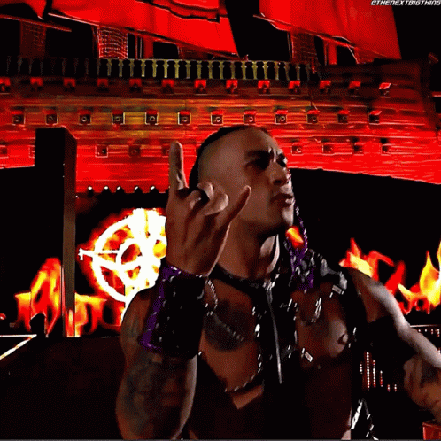 A Wrestler Is Giving The Middle Finger In Front Of A Red Background That Says Thenextbigthing GIF
