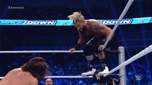 a wrestler is jumping over a rope while another wrestler is watching
