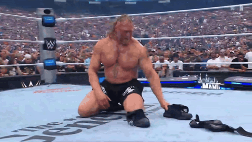 A Wrestler Is Kneeling Down In A Wrestling Ring That Says The Reigns On It GIF