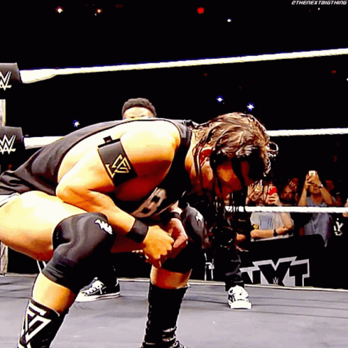 A Wrestler Is Kneeling Down In A Wrestling Ring While A Crowd Watches GIF
