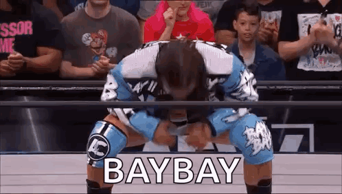 A Wrestler Is Kneeling Down In Front Of A Crowd And The Word Baybay Is Written On The Screen . GIF