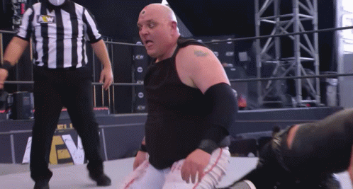 A Wrestler Is Kneeling Down In Front Of A Referee Wearing A Shirt That Says Aew GIF