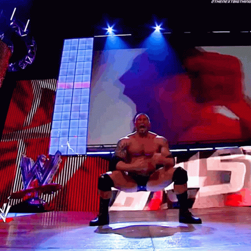 A Wrestler Is Squatting Down On A Stage With The Number 15 In The Background GIF