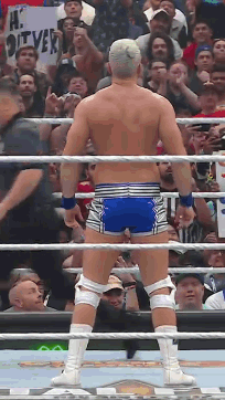A Wrestler Is Standing In A Ring With A Crowd Behind Him And A Sign That Says Hi Oliver GIF