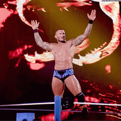 A Wrestler Is Standing In A Ring With His Arms In The Air And A Screen Behind Him That Says Wrestling GIF