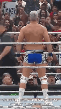 A Wrestler Is Standing In A Ring With His Back To The Camera . GIF