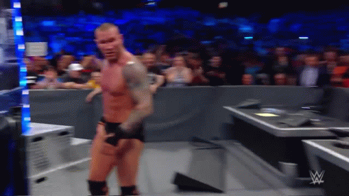A Wrestler Is Standing In Front Of A Crowd While Wearing Shorts And Boxing Gloves GIF