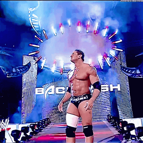 A Wrestler Is Standing In Front Of A Sign That Says Back GIF