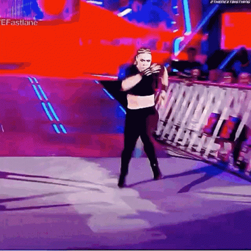 A Wrestler Is Standing On A Stage In Front Of A Crowd And Holding A Rope . GIF