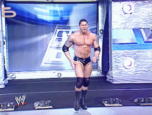 A Wrestler Is Standing On A Stage In Front Of A Large Screen With The Letter W On It GIF