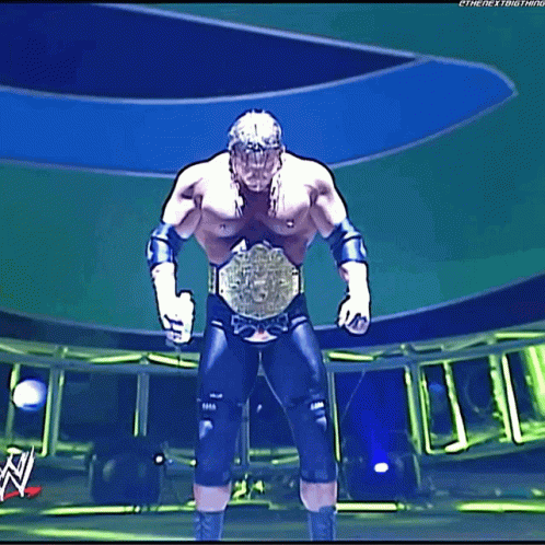 A Wrestler Is Standing On A Stage With A Wwe Logo In The Background GIF
