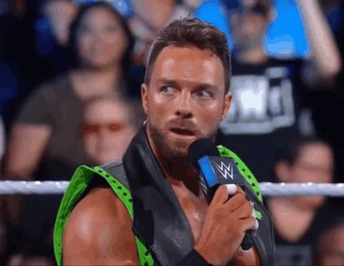 A Wrestler Is Talking Into A Microphone In A Ring . GIF