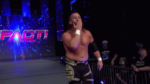 A Wrestler Is Walking In Front Of A Sign That Says Impact Wrestling . GIF