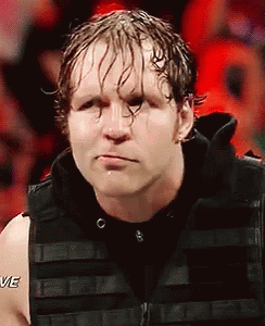 A Wrestler Is Wearing A Black Vest And Making A Funny Face While Standing In Front Of A Crowd . GIF